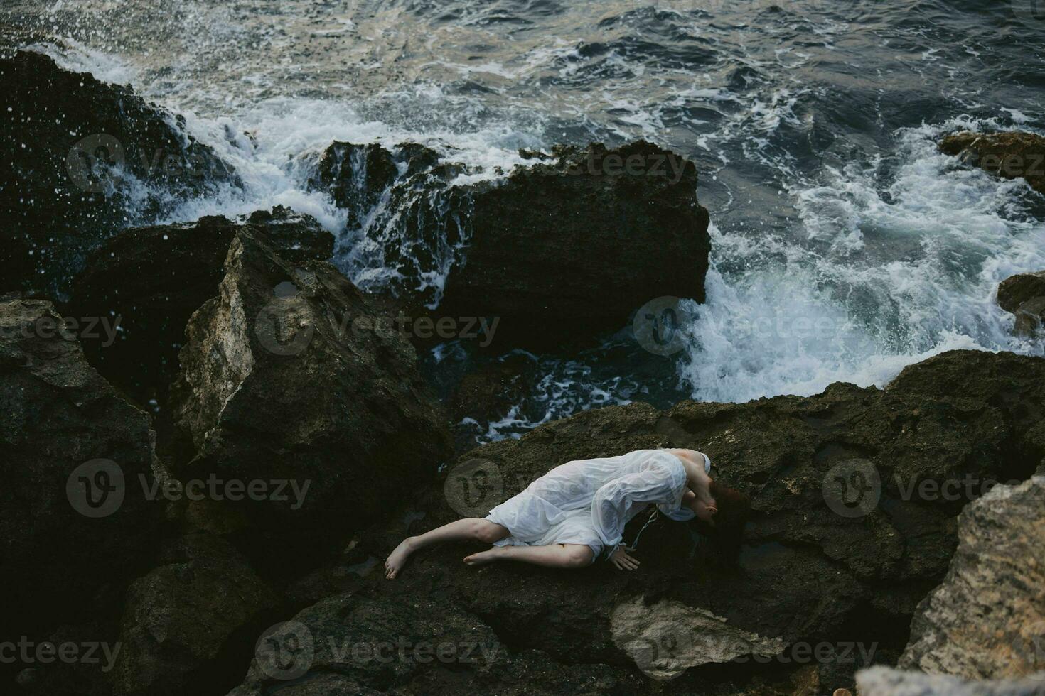 woman lying on rocky coast with cracks on rocky surface landscape photo