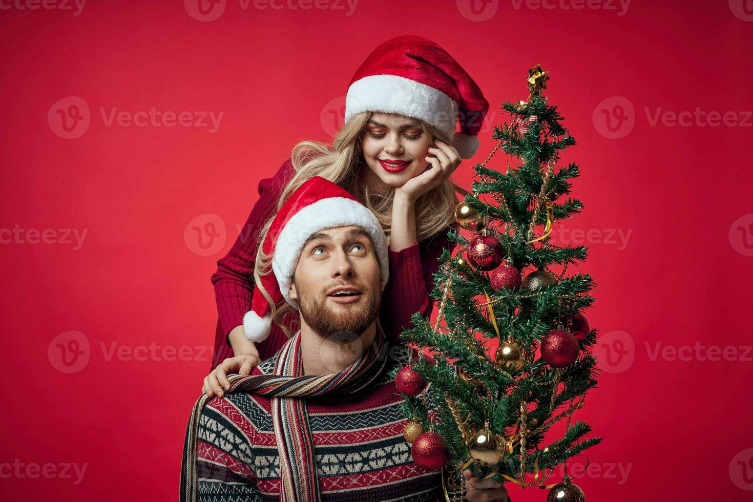 man and woman christmas tree decoration fun holiday red background photo