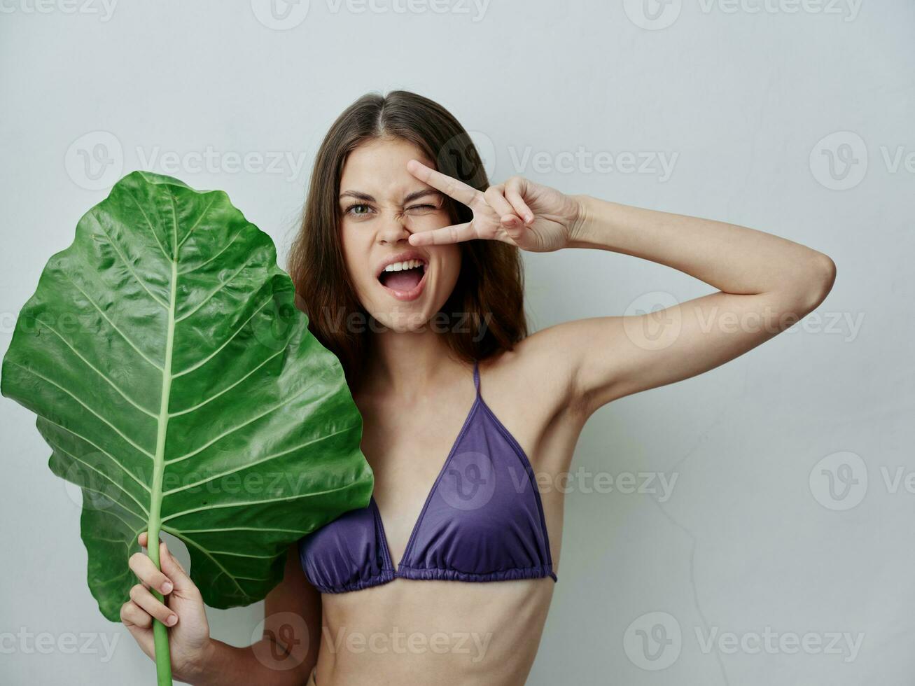cheerful woman holding hands near face green leaf swimsuit emotions close-up photo