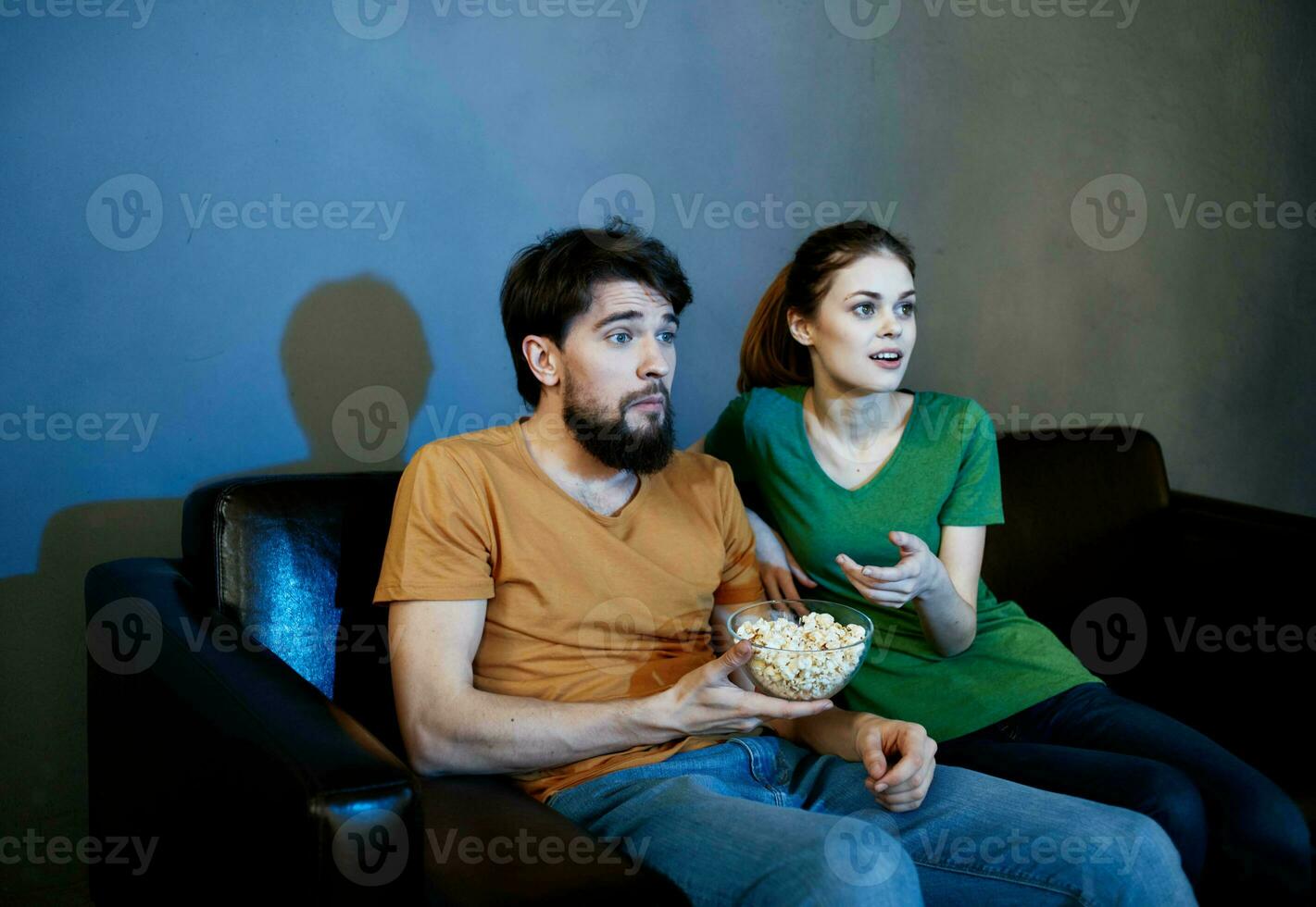 Handsome man and young woman on sofa indoors watching TV in the evening photo