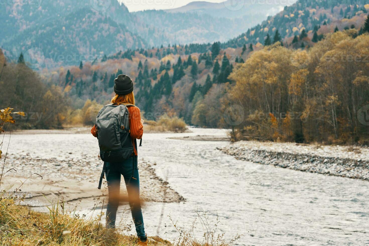 woman traveler walks in nature in the mountains near the river landscape model hat red hair photo