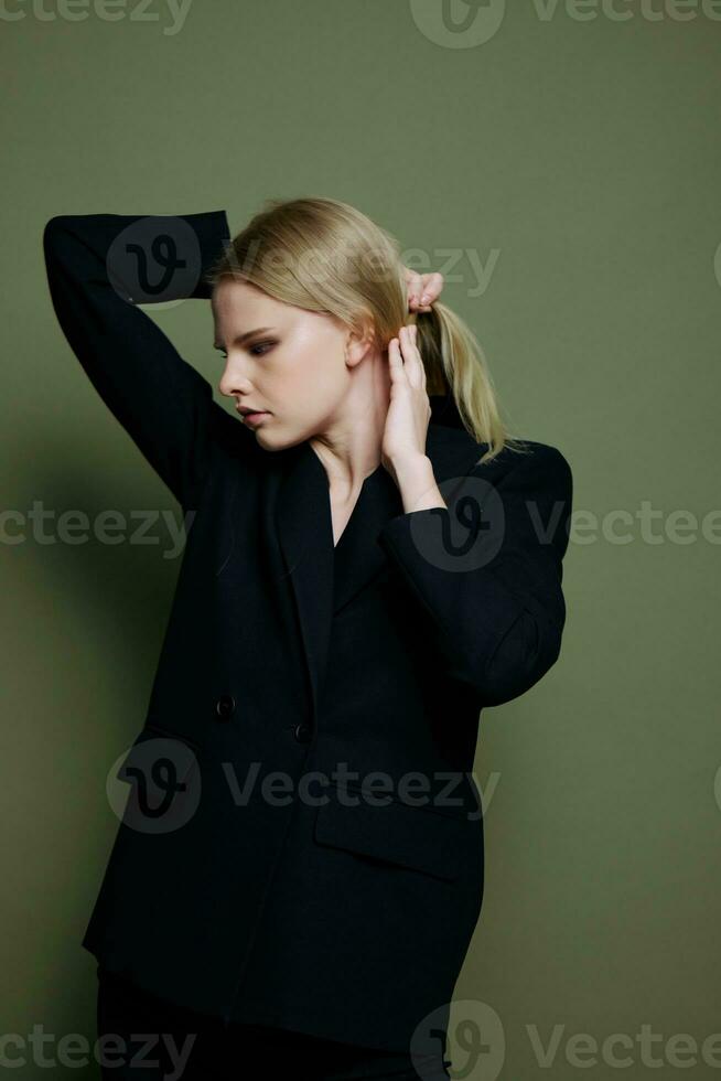 Serious strict attractive lady holding her hair posing isolated on a green background in the studio photo