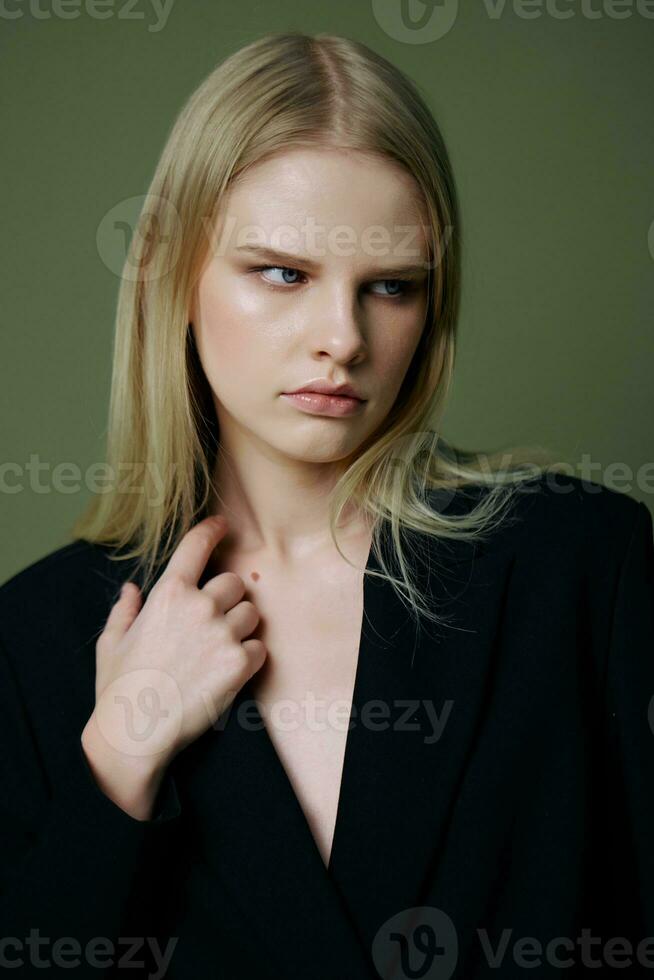 The head portrait of a charming beautiful girl in a black jacket poses on a green background in the studio. Cool banner for brands. Cool offer for design photo