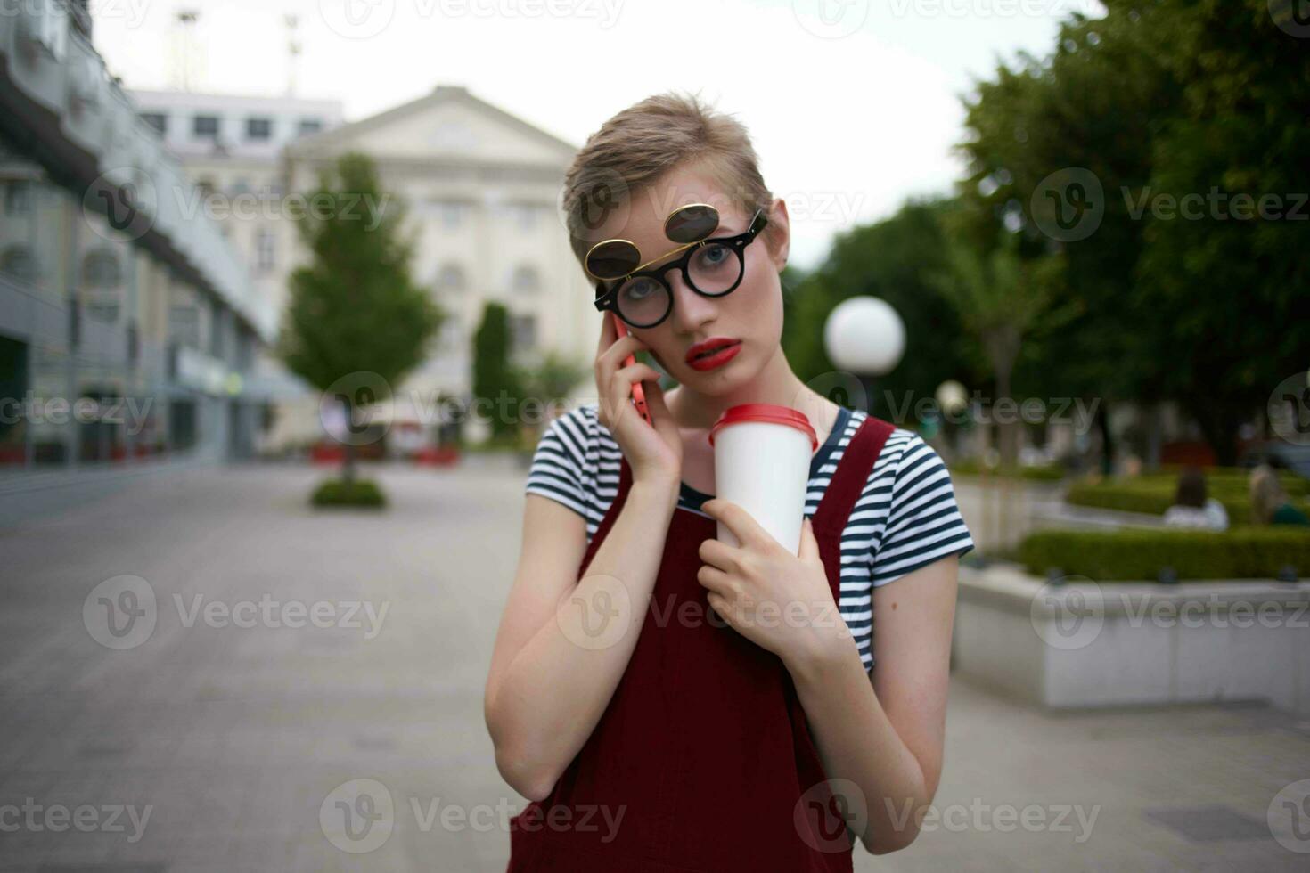 a woman with glasses walks around the city a glass with a drink leisure communication photo