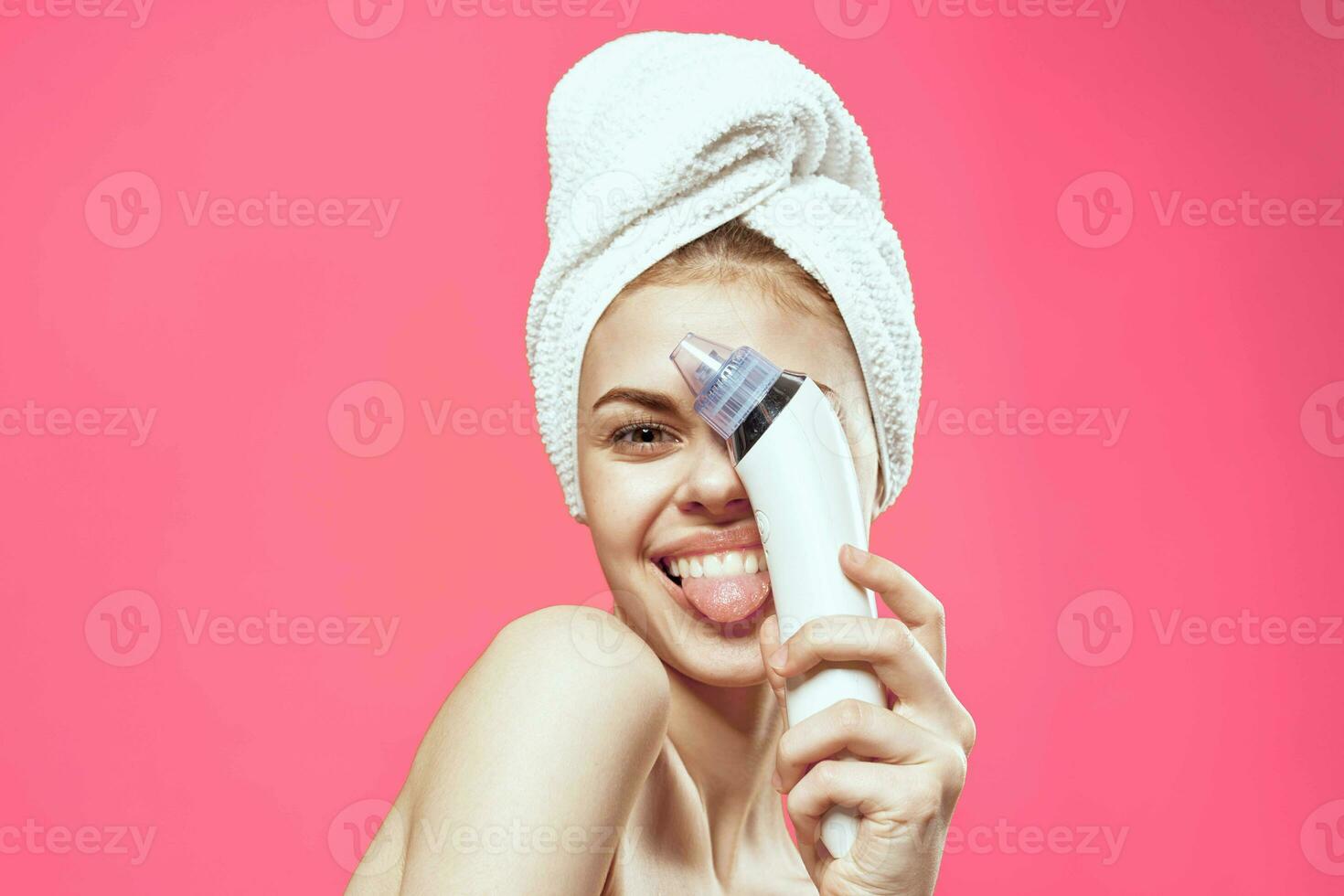 woman with towel on head cleaning face skin care pink background photo