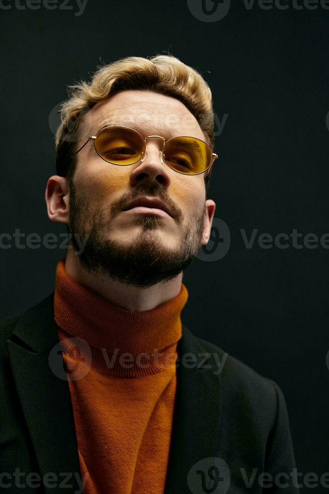 retrato de un de moda hombre con lentes y un naranja suéter chaqueta tendencia de el otoño temporada nuevo artículos foto