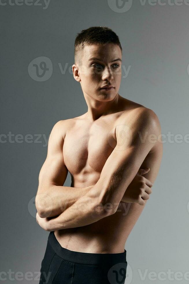 sexy bodybuilder crossed arms over chest on gray background cropped view close-up photo