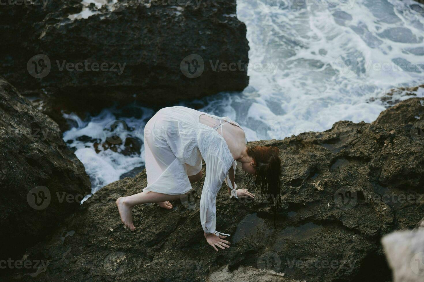 woman climbs rocky rocks by the ocean travel photo