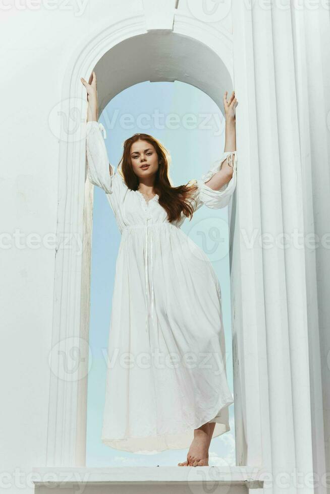 pretty woman in a white dress in the window in the form of an angel photo