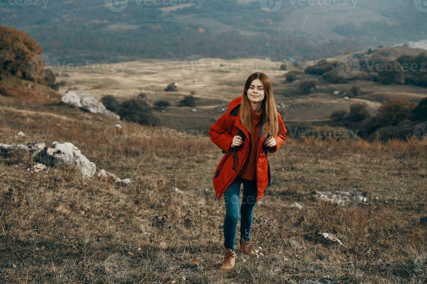 travel tourism young woman in red jacket and jeans with backpack in the mountains in autumn photo