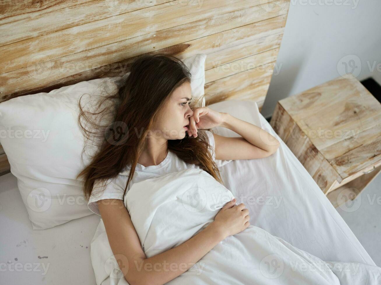 woman with unhappy facial expression lies in bed upset photo