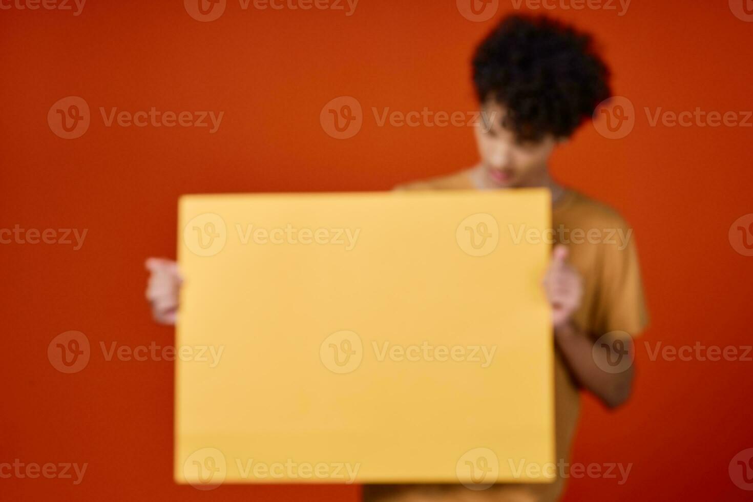 guy with curly hair yellow poster in hands studio advertising photo