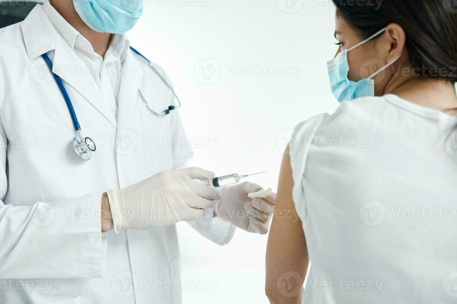 the doctor with a syringe in his hand injects the vaccine in protective gloves photo