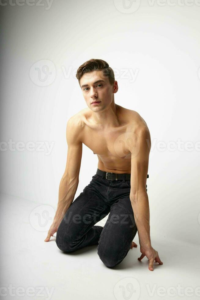 Man kneeling in black trousers nude torso posing lifestyle photo