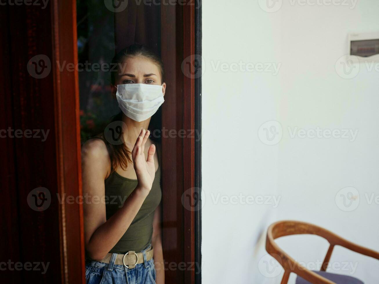 mujer en médico máscara mirando fuera el ventana triste Mira prohibición foto