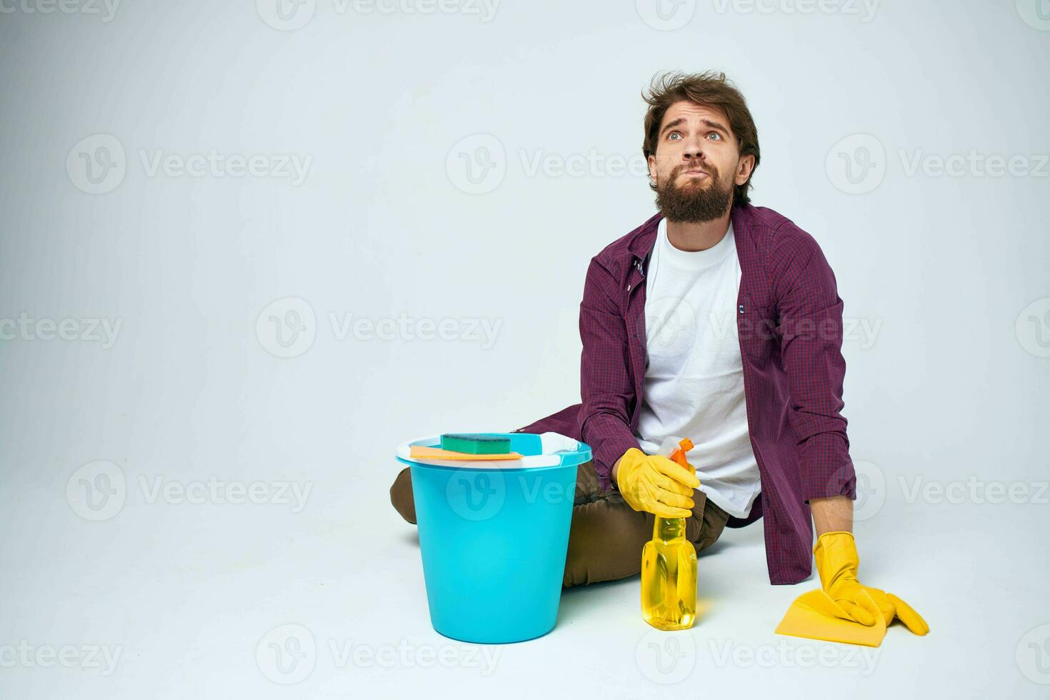 A man lies on the floor with a bucket of detergent cleaning service light background photo