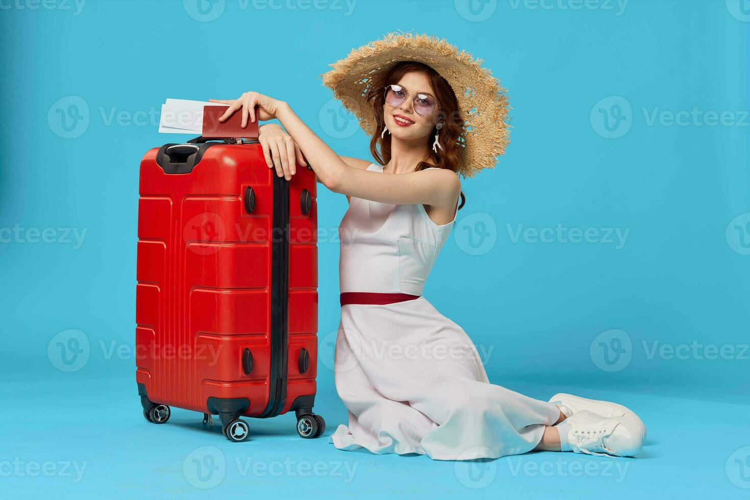 cheerful woman with red suitcase sitting on the floor emotions isolated background photo