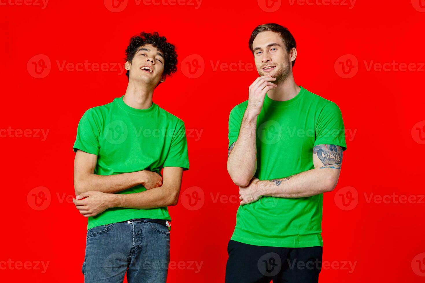 two friends in green t-shirts are standing next to tin with their hands emotions red background photo