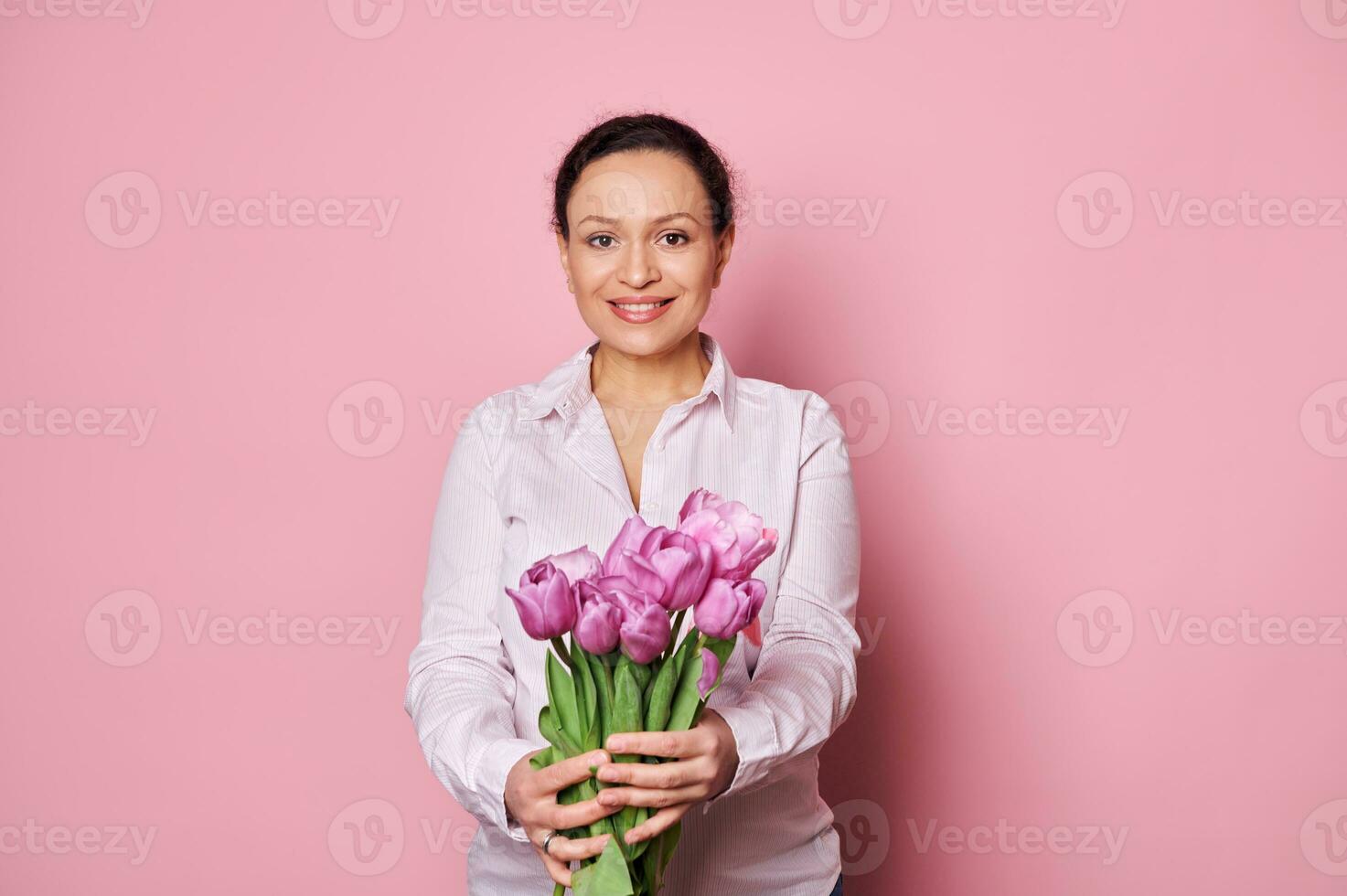 sonriente mujer con rosado conciencia cinta, participación fuera a cámara un ramo de flores de tulipanes, secundario pecho cáncer supervivientes foto