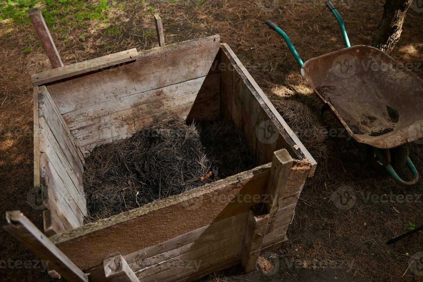 compost montón. compost pozo en el trama de tierra. de madera caja para fertilizante y desperdiciar. humus con tu propio manos. foto