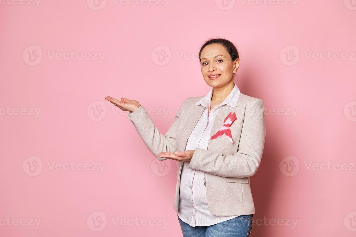 embarazada mujer, vistiendo rosado satín cinta - emblema de luchando pecho cáncer, demostración Copiar espacio en aislado antecedentes foto