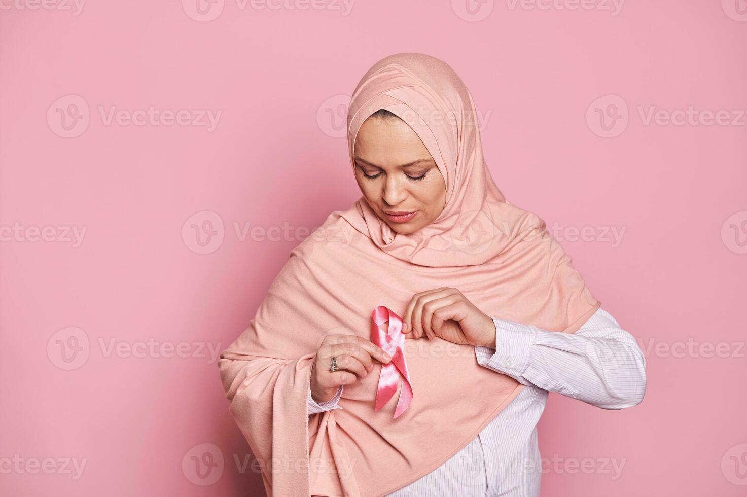 de cerca retrato de un musulmán bonito mujer poniendo en un rosado satín cinta en su hiyab pecho cáncer conciencia Campaña foto