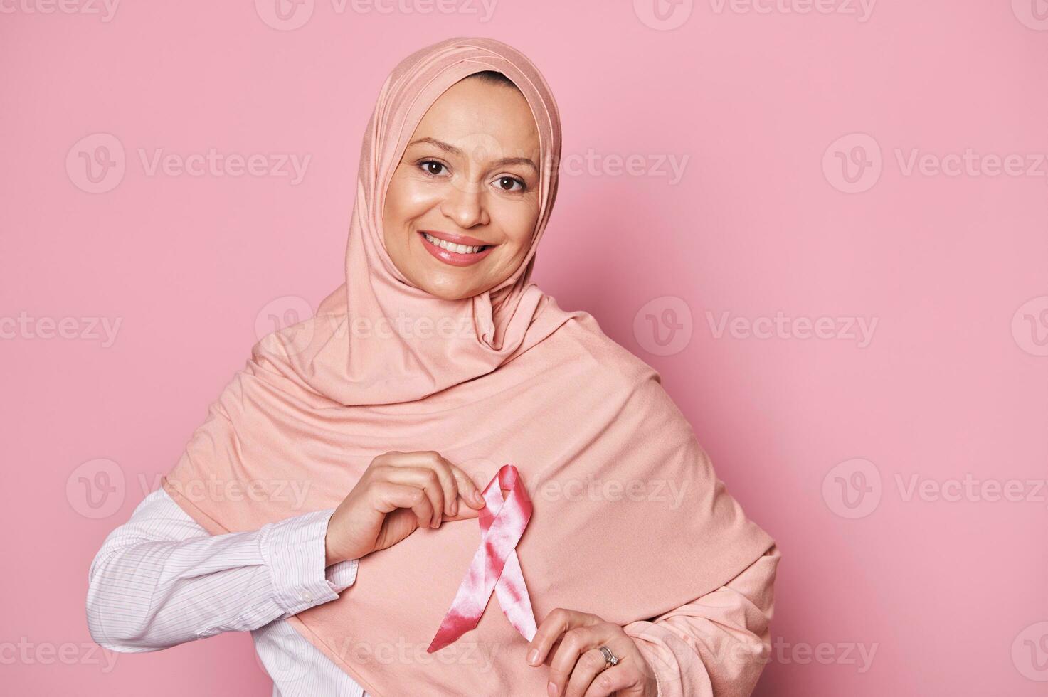 musulmán mujer en hiyab, vistiendo rosado satín cinta, apoyos cáncer pacientes sobrevivientes mundo pecho cáncer conciencia día foto