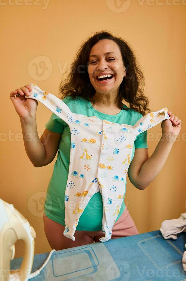 lleno de alegría esperando mujer con bebé mono, sonriente a cámara, expresando positivo emociones terminado naranja antecedentes foto