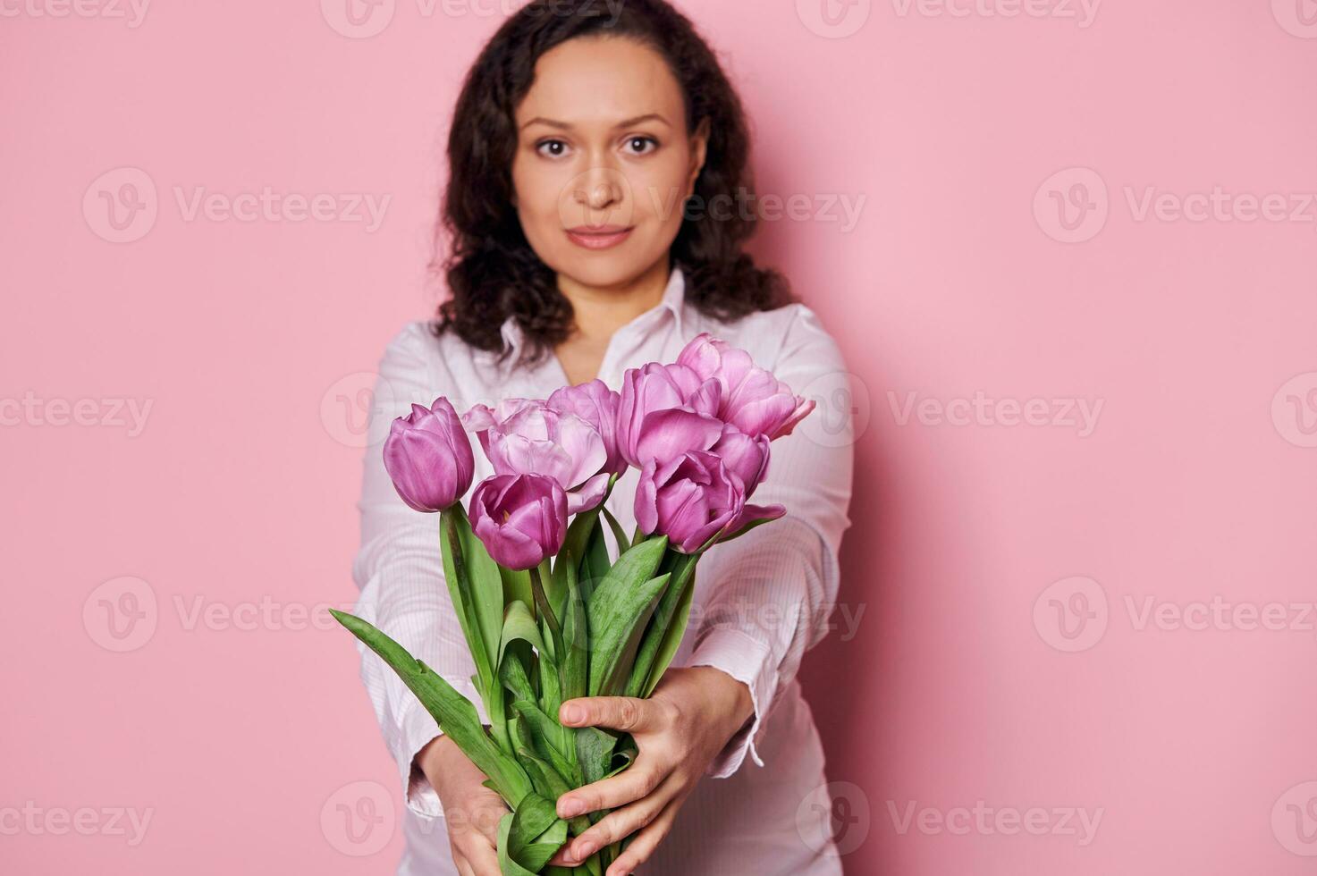 Details  beautiful purple tulips in hands of charming woman holding out at camera a bouquet for festive occasion photo