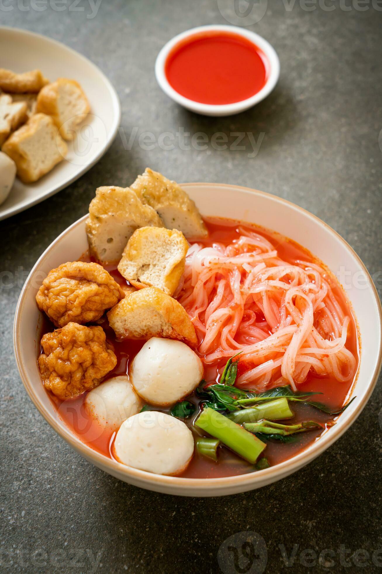 small flat rice noodles with fish balls and shrimp balls in pink soup