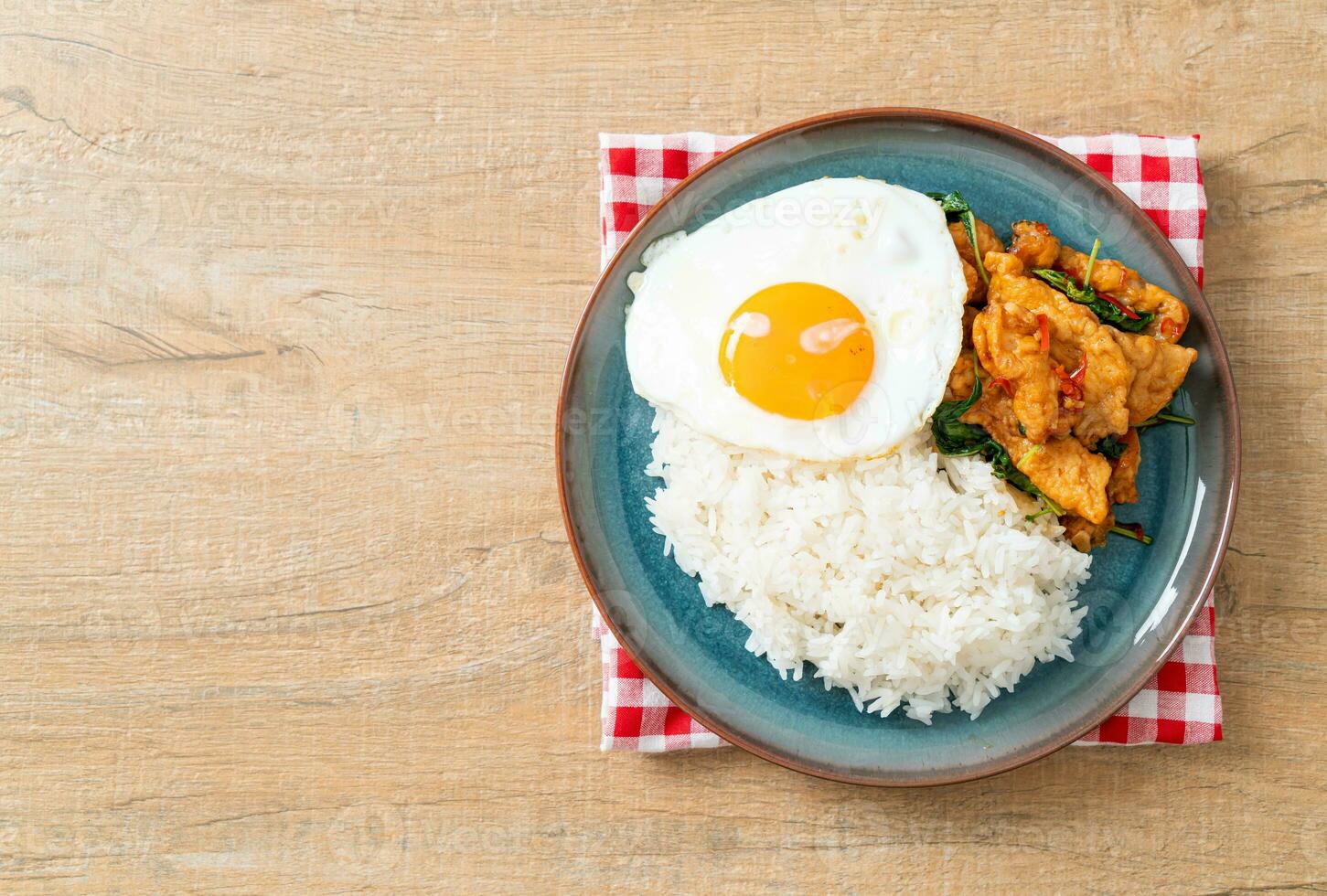 stir-fried fried fish with basil and fried egg topped on rice photo