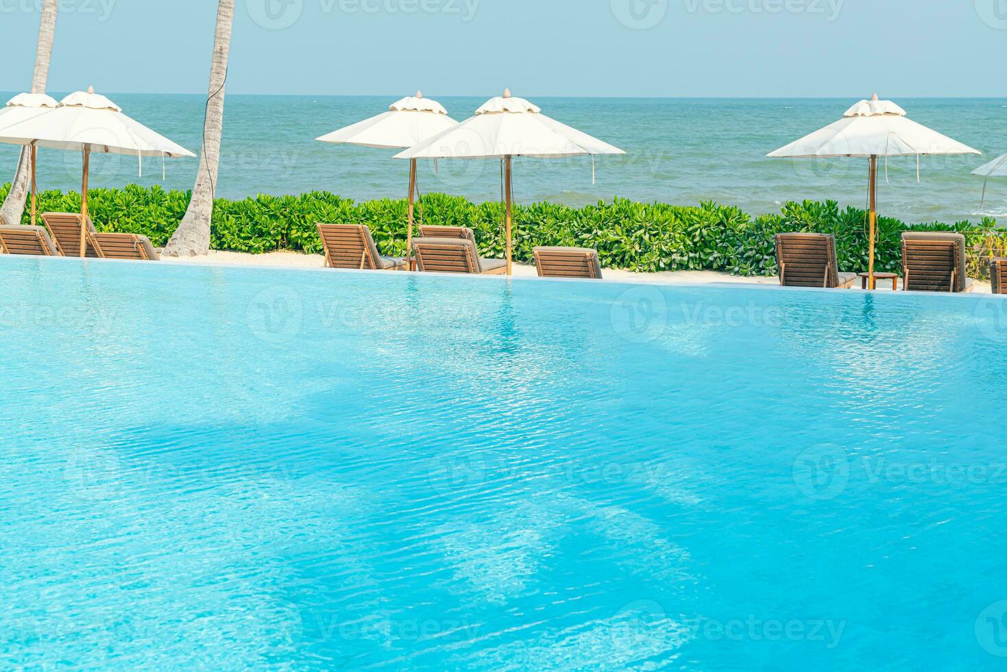 umbrella with bed pool around swimming pool with ocean sea background photo