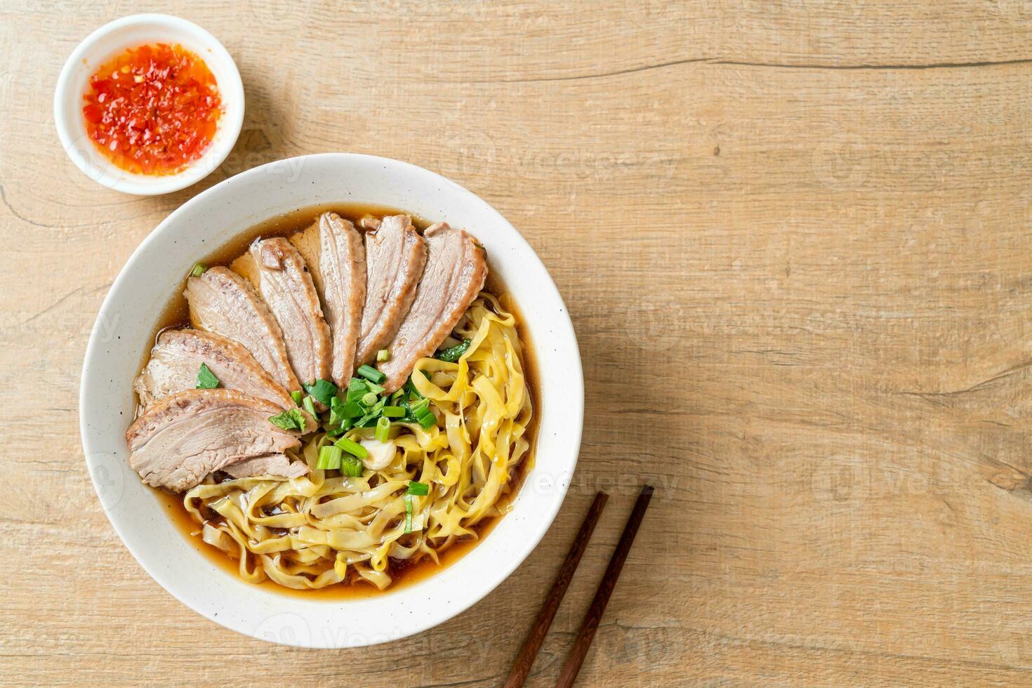 tallarines de huevo con pato guisado en sopa marrón foto