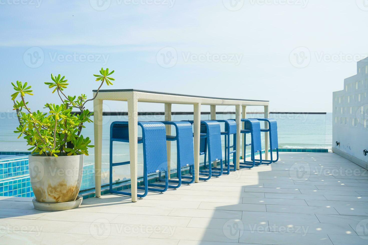 desk and bar stool near swimming pool with sea background 23739008