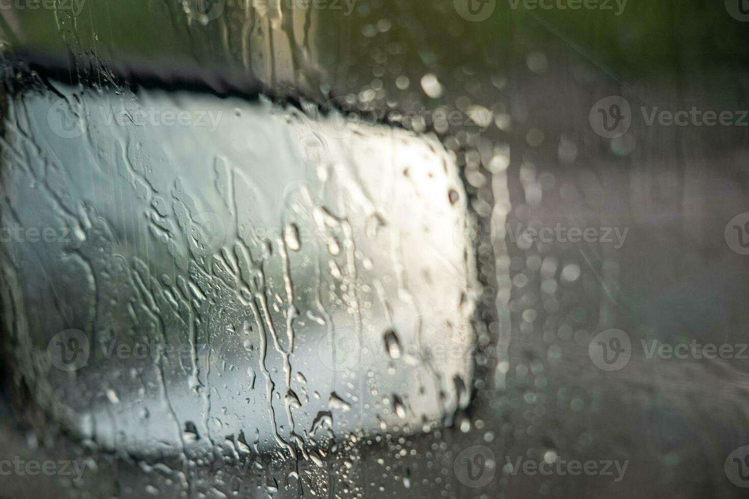 Raindrops on the car window and rearview mirror. Driving in the rain. sad vibe photo