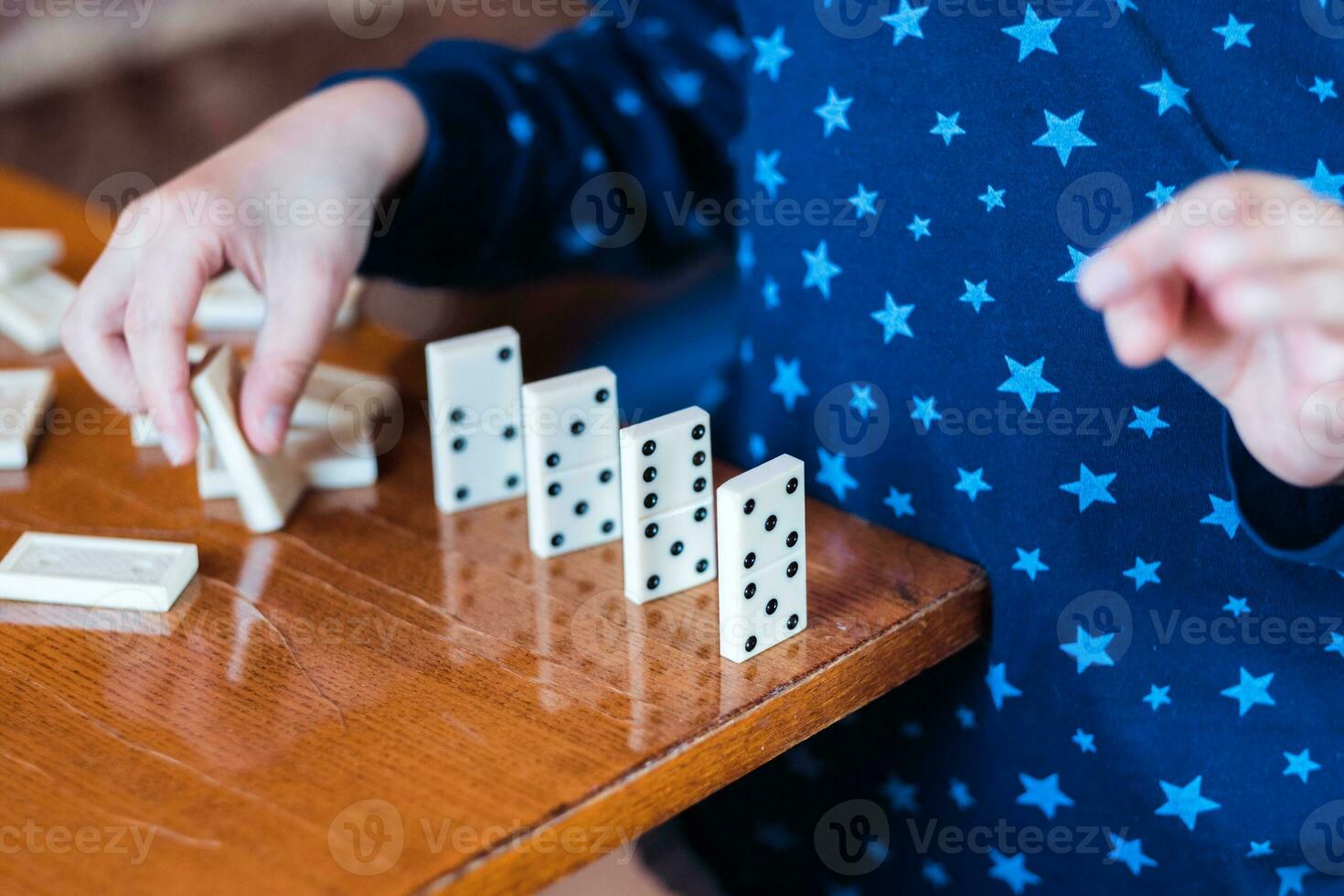 Boy playing with dominoes, close up. Build a domino fence, close up photo
