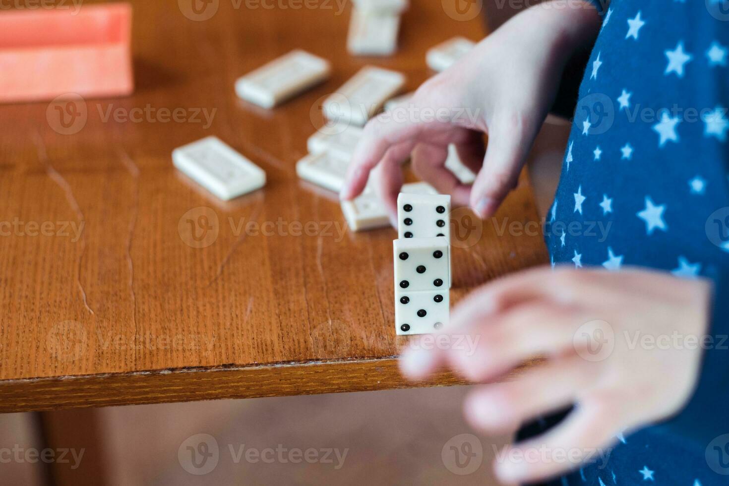 Boy playing with dominoes, close up. Build a domino fence, close up photo