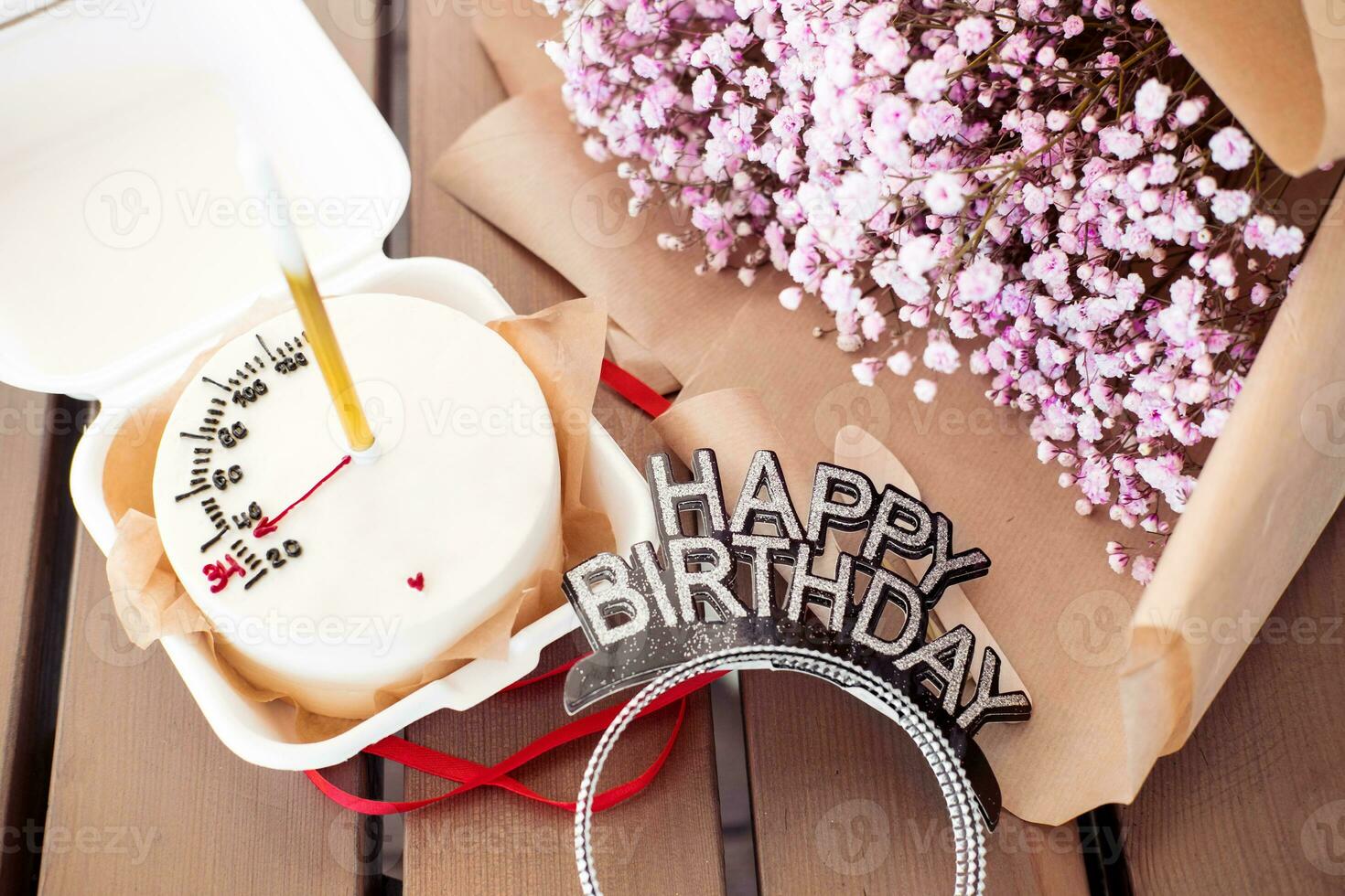 bento pastel con un vela con un ramo de flores de rosado Gypsophila en un de madera mesa, en un cafetería. pequeño sorpresa para un muchachas cumpleaños foto