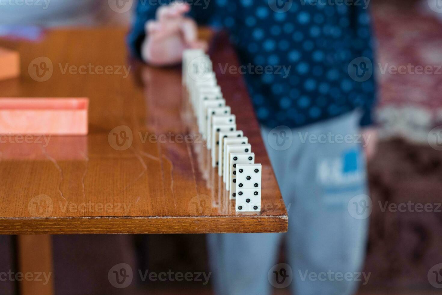 Boy playing with dominoes, close up. Build a domino fence, close up photo