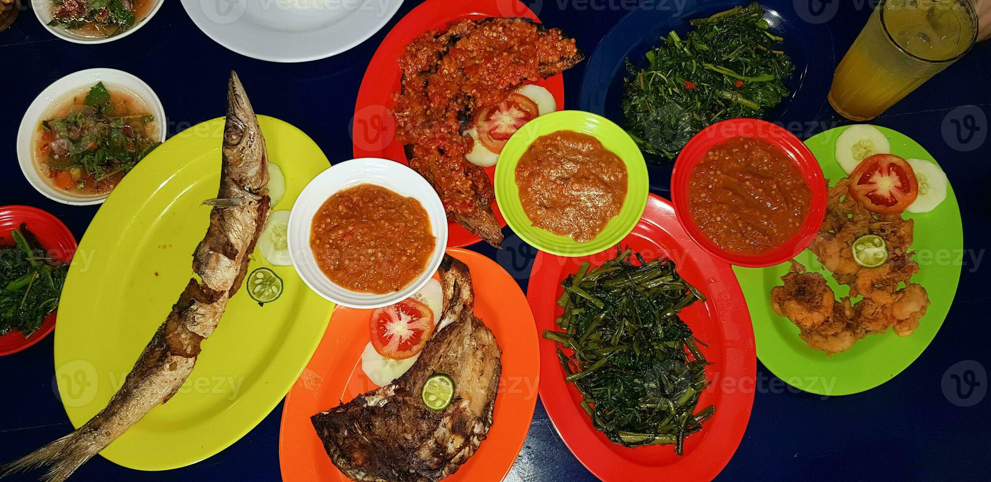 Mariscos plato servido en el mesa y plato desde encima con diferente tipo de plato desde frito pescado barracuda, pargo, atún mandíbulas, y además mezcla de tropical vegetales foto