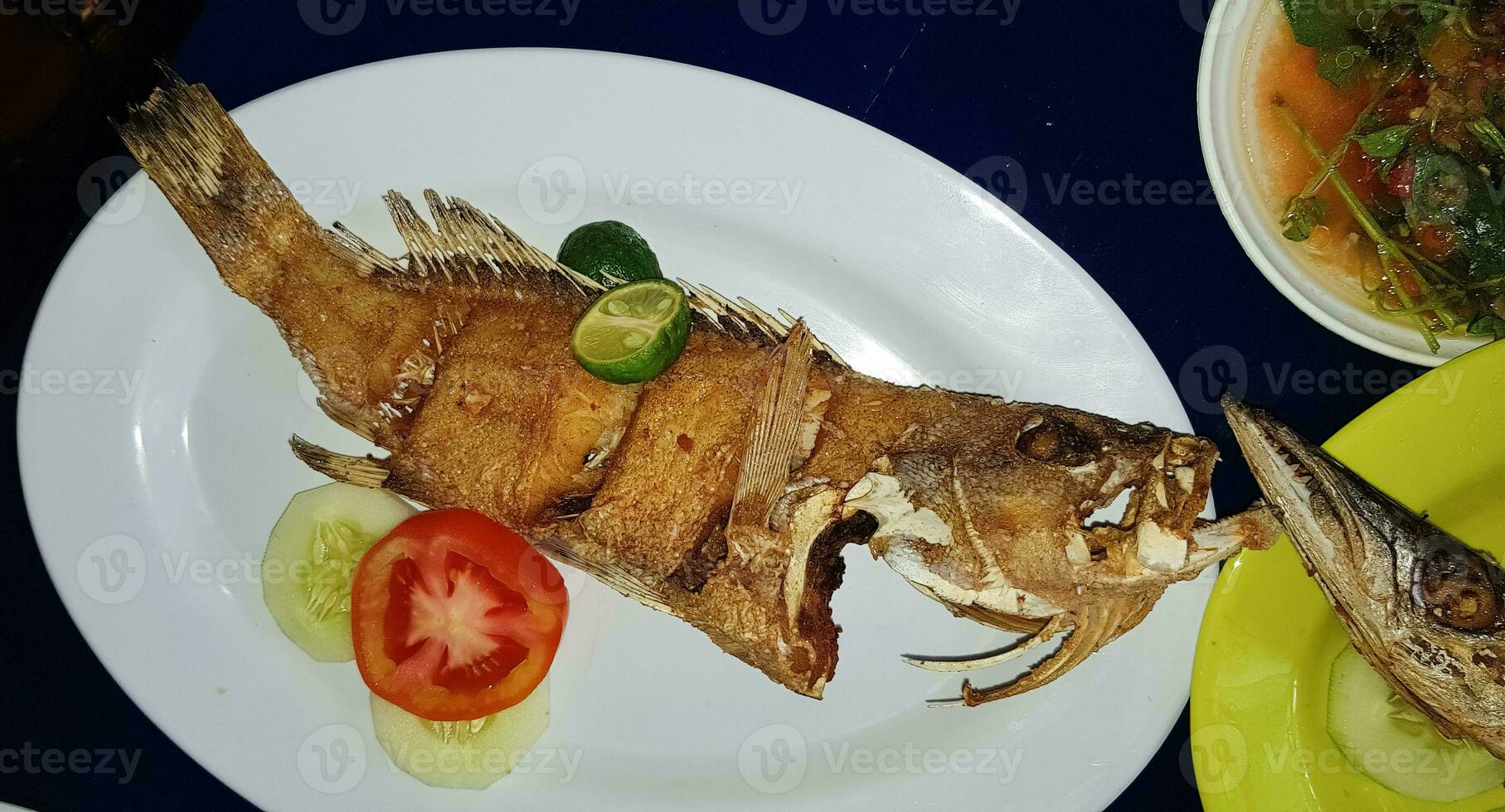 Mariscos plato servido en el mesa y plato desde encima con diferente tipo de plato desde frito pescado barracuda, pargo, atún mandíbulas, y además mezcla de tropical vegetales foto