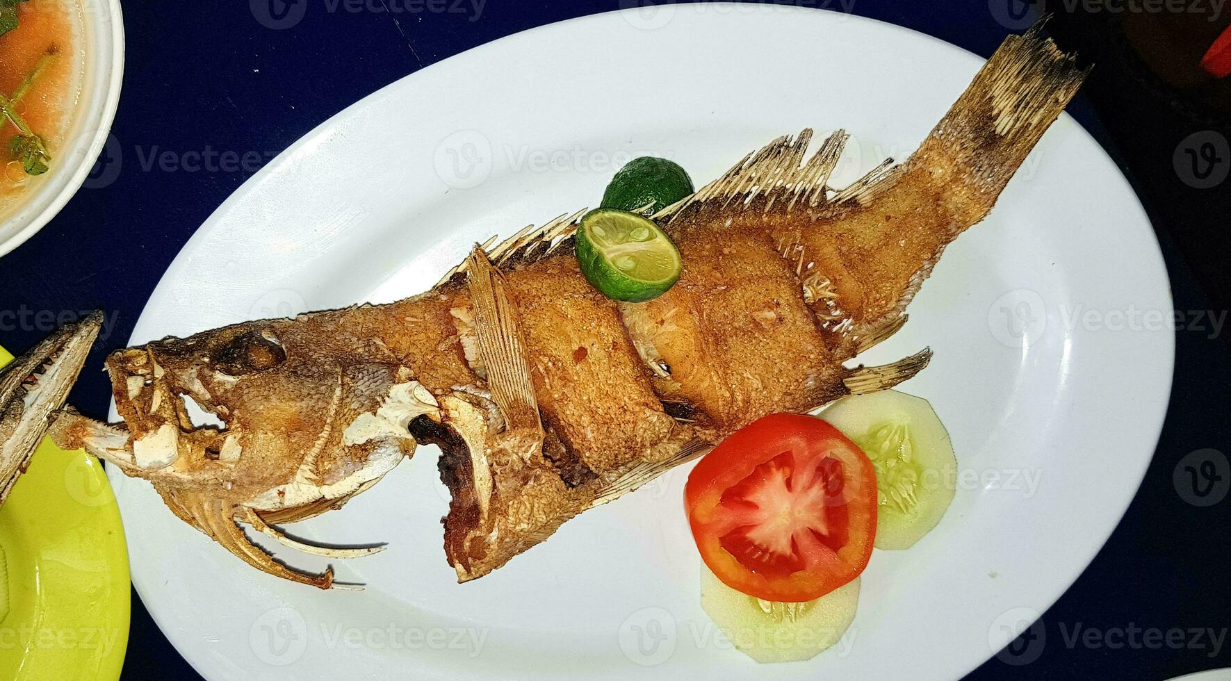 Mariscos plato servido en el mesa y plato desde encima con diferente tipo de plato desde frito pescado barracuda, pargo, atún mandíbulas, y además mezcla de tropical vegetales foto