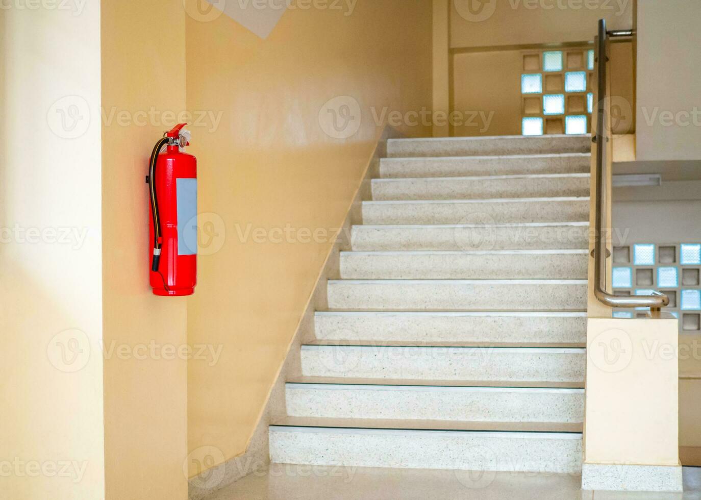 A fire extinguisher hangs up the stairs. Fire safety concept. photo