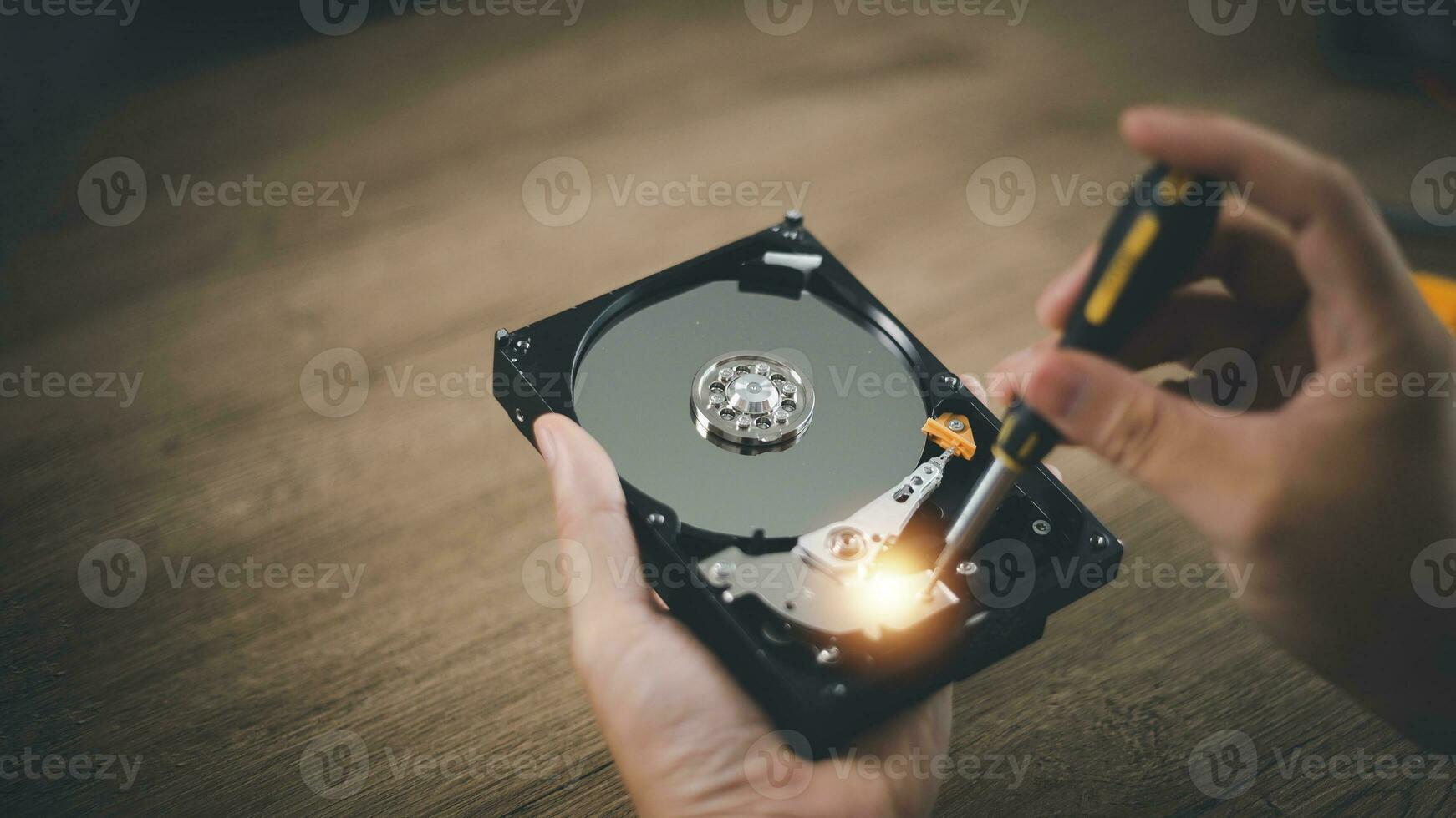 Close up of hard disk internal mechanism hardware. HDD in hand with a screwdriver photo