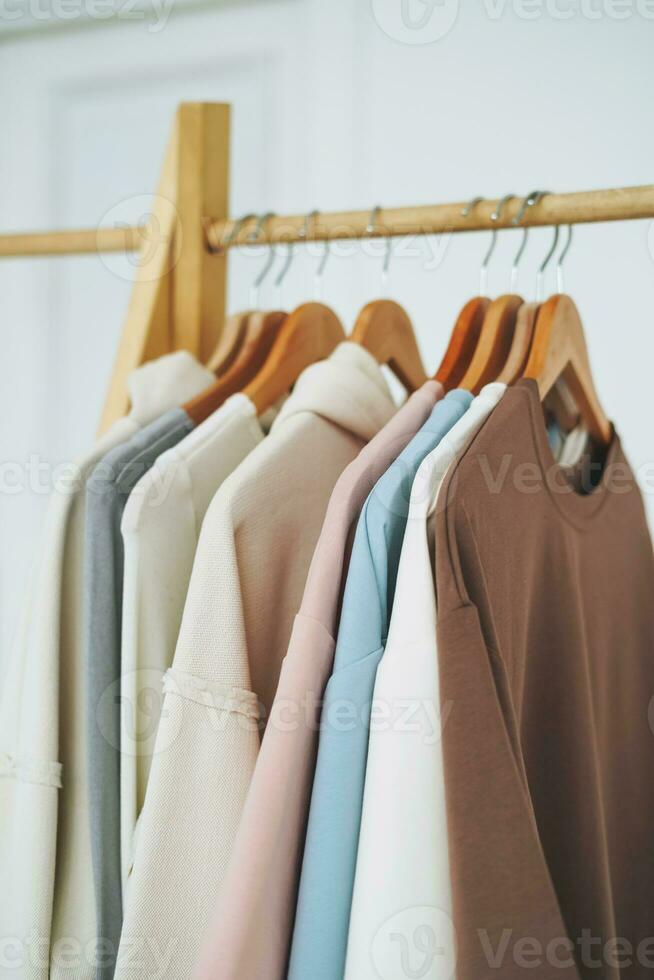 Cotton tops sweatshirts in natural tones on wooden shelf in bright room photo