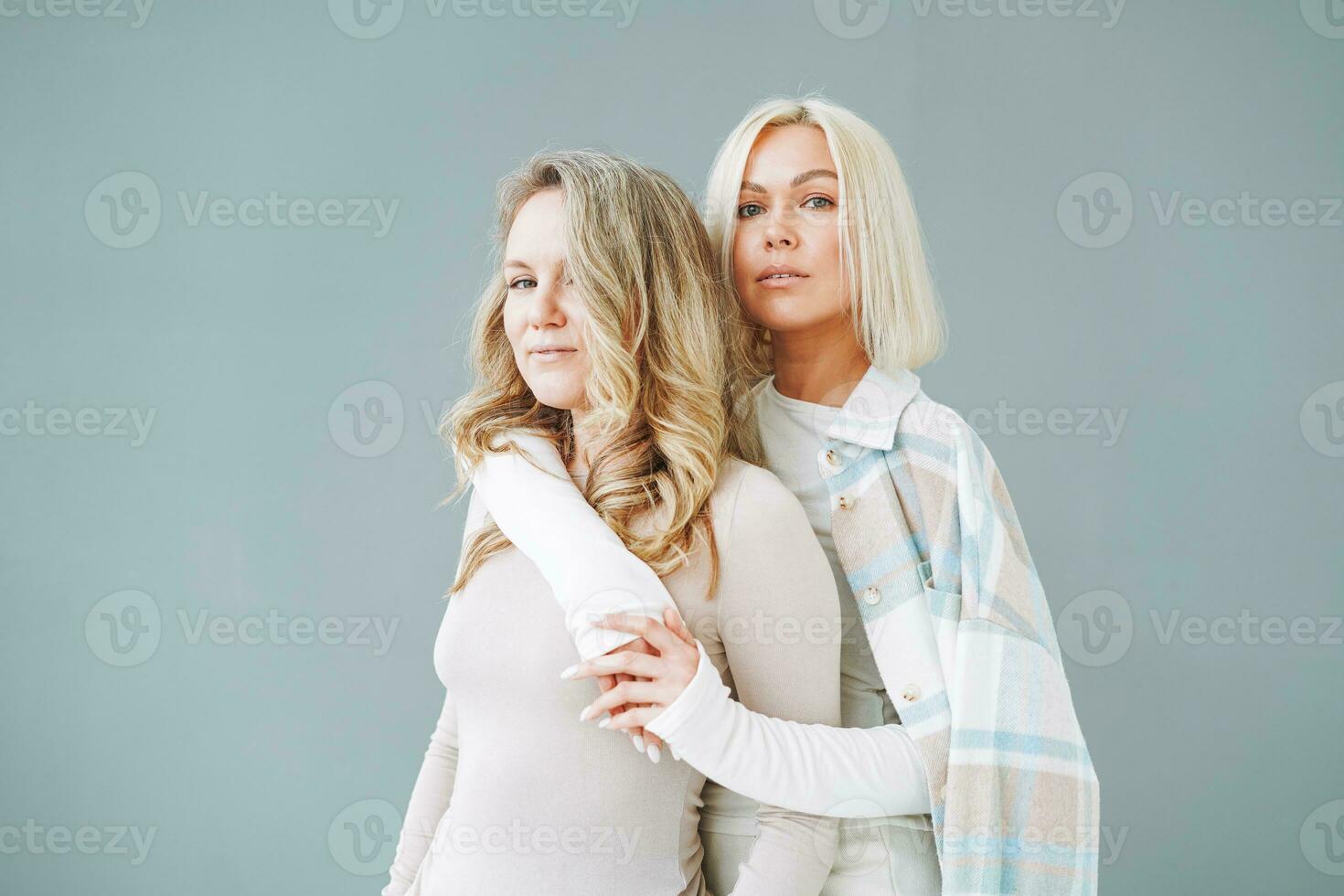 Portrait of young blonde women friends in sportswear on background of grey wall photo