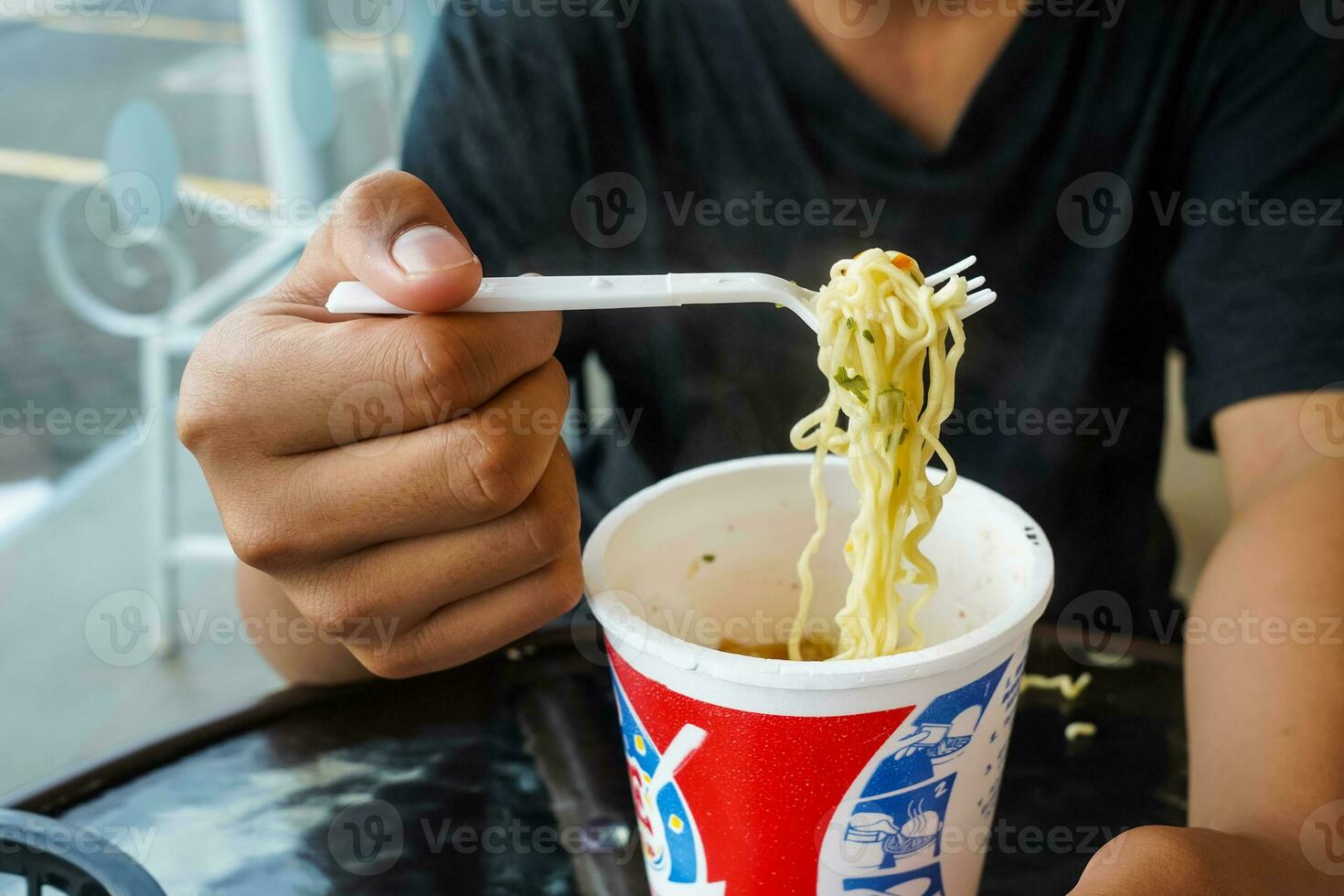 instant noodles, noodle soup in a cup, boys hand feeding ready to eat noodles photo