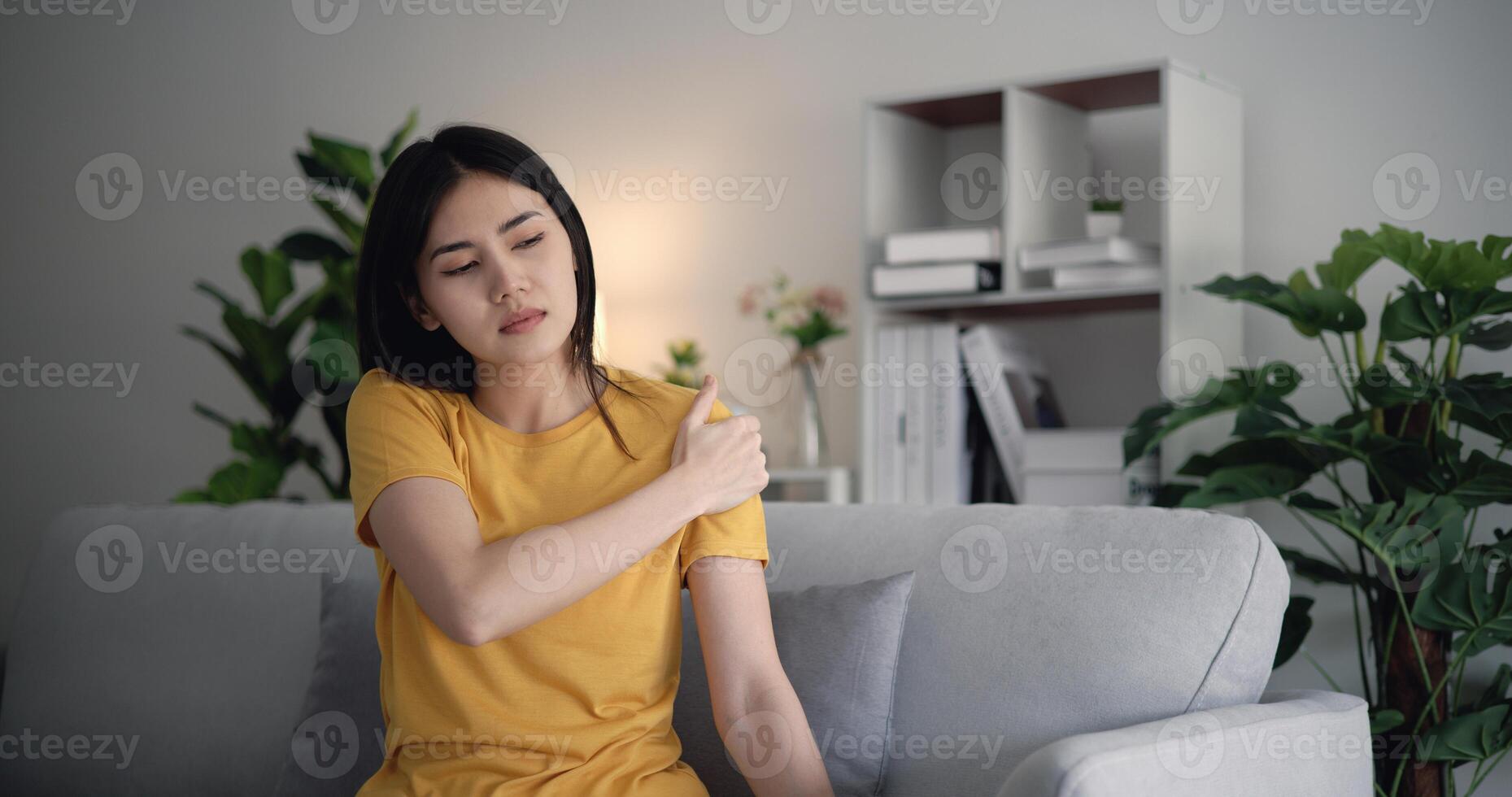 Young Asian woman shoulder pain in the living room at home. photo