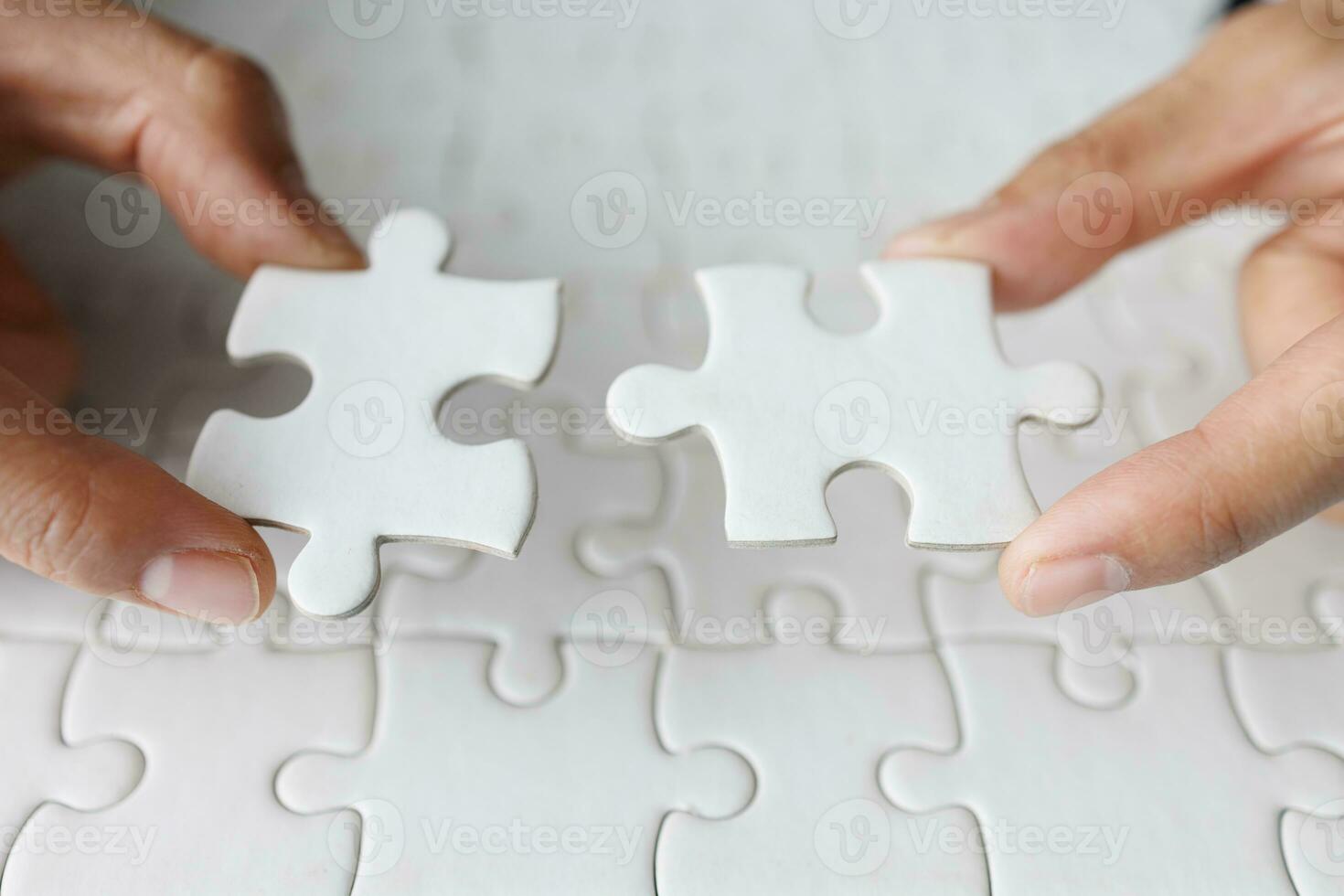 Business woman hand is trying to connect couple White jigsaw puzzle piece on a blue background. Symbol of association and connection. Concept of business strategy. photo