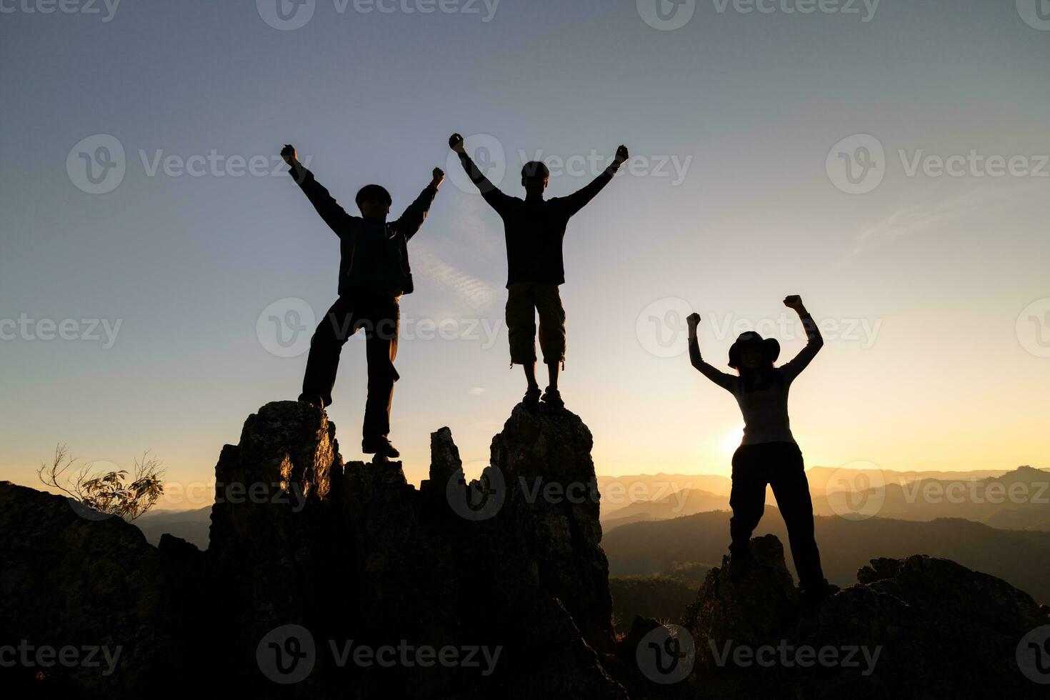 Silhouette of happy teamwork with success gesture standing on the top of mountain, business teamwork concept, business victory, achieve business goal. photo